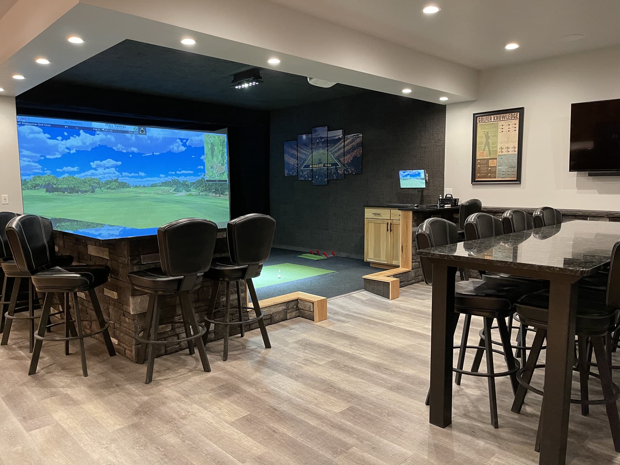 Executive Suite with a golf course on the 17-foot simulator screen, leather bar stools and a high-top table